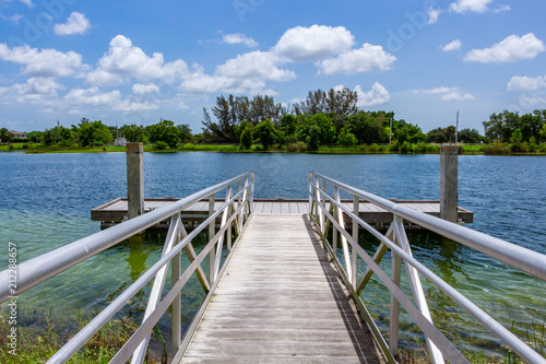 Obraz na plátně Ramp to boat dock on blue green lake with trees, vegetation and blue sky - Vista