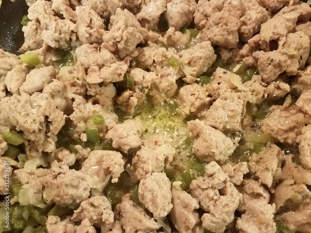 ground turkey meat sizzing in a frying pan with green peppers