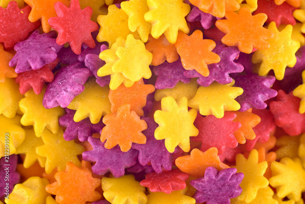 Colourful sugar candy flowers background, copy space. Closeup of pile violet, yellow and orange chocolate candies. Candy texture. Candy pattern. Sweets background. Top view, flat lay Colourful sugar candy flowers background, copy space. Closeup of pile violet, yellow and orange chocolate candies. Candy texture. Candy pattern. Sweets background. Top view, flat lay
