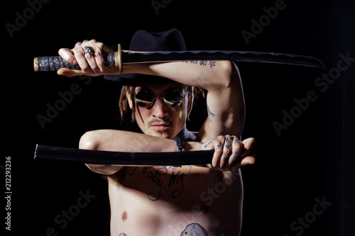 Warrior posing with sword with tattooed hands, neck and chest