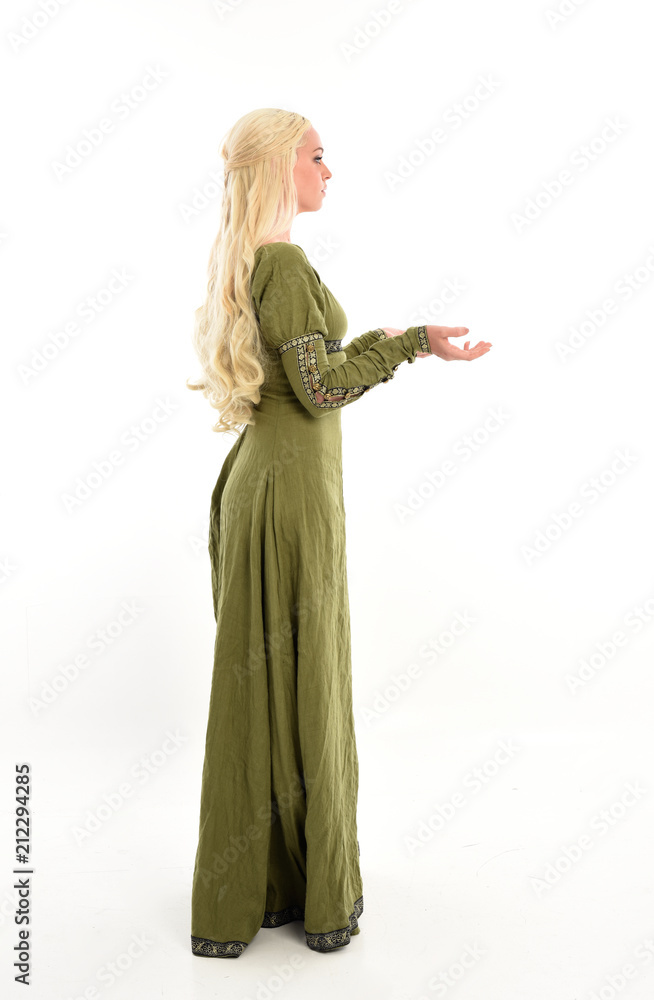 full length portrait of a blonde girl wearing green medieval gown, stand pose, isolated on white studio background.