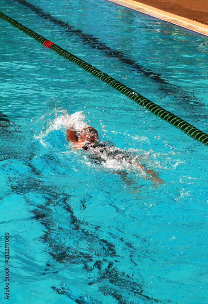 Swimmer swims backstroke or back crawl in a swimming pool for competition or race