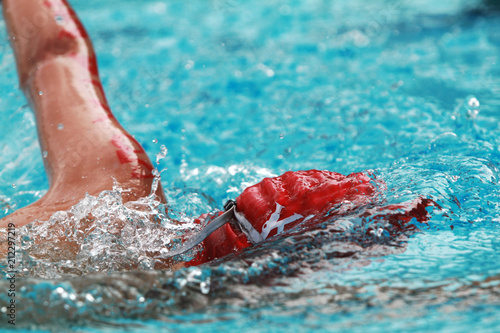 Close up young boy swimmer with red cap swim free style or forward crawl in a swimming pool for competition or race