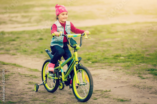 Child riding bike. Kid on bicycle in sunny park. Little girl enjoying bike ride on her way to school on warm summer day. Preschooler learning to balance on bicycle . Sport for kids.