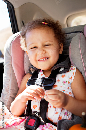 Little girl smiling in her car seat.