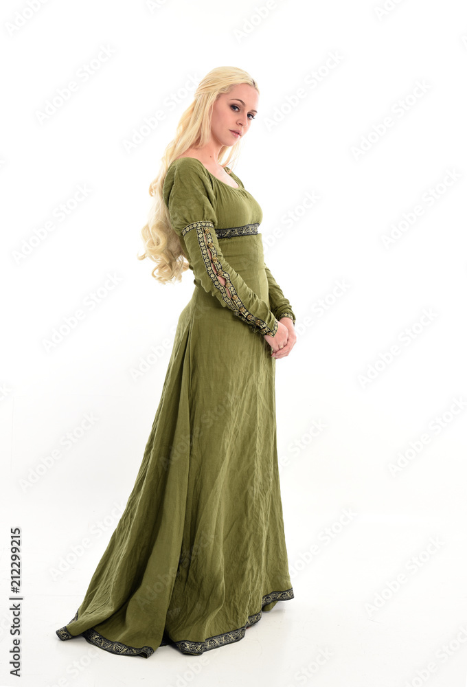 full length portrait of a blonde girl wearing green medieval gown, stand pose, isolated on white studio background.