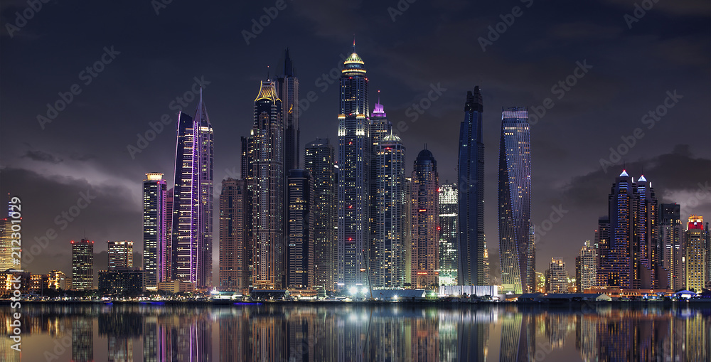 Fototapeta premium Wolkige Skyline von Dubai am Abend mit Wasser-Spieglung