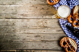 Oktoberfest food menu, bavarian pretzels with beer bottle mug on old rustic wooden background, copy space above
