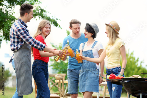 Young people having barbecue with modern grill outdoors