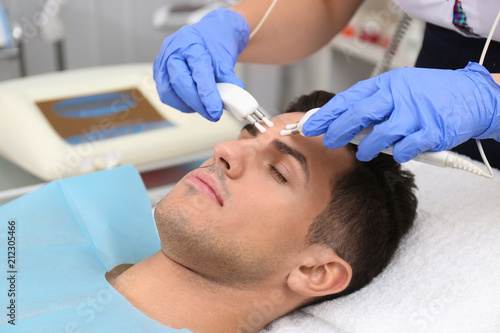 Young man undergoing microcurrent therapy in beauty salon
