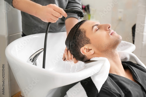 Hairdresser washing client's hair in beauty salon