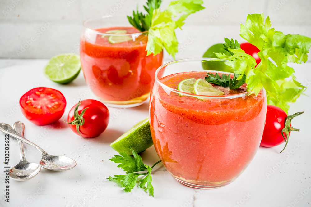 Summer veggie food, Cold soup gazpacho in glasses with with fresh celery, parsley and lime juice. White marble background copy space Summer veggie food, Cold soup gazpacho in glasses with with fresh celery, parsley and lime juice. White marble background copy space