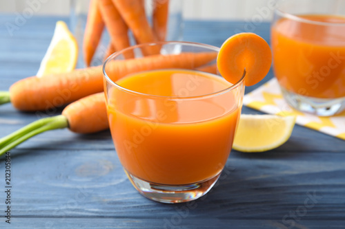 Glass with fresh carrot juice on wooden table