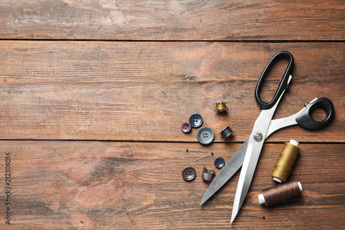 Set of tailoring accessories on wooden background, top view