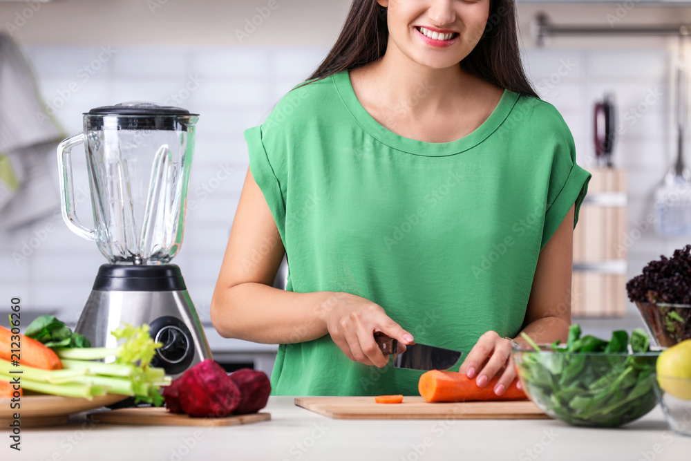 Young woman preparing tasty healthy smoothie at table in kitchen Young woman preparing tasty healthy smoothie at table in kitchen