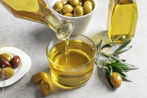 Pouring fresh olive oil into glass on table