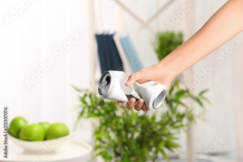 Woman holding crumpled aluminum can on blurred background. Metal waste recycling