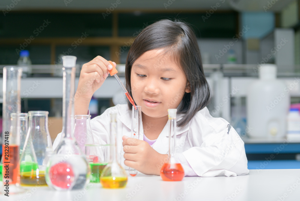 Happy little scientist in lab coat making experiment Happy little scientist in lab coat making experiment