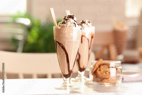 Glass with delicious milk shake on table indoors