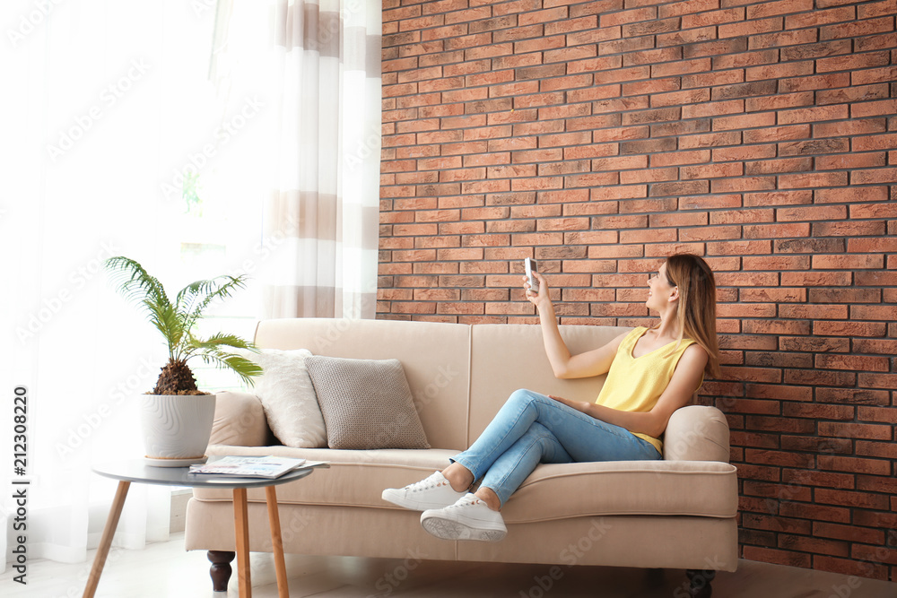 Woman with air conditioner remote at home Woman with air conditioner remote at home