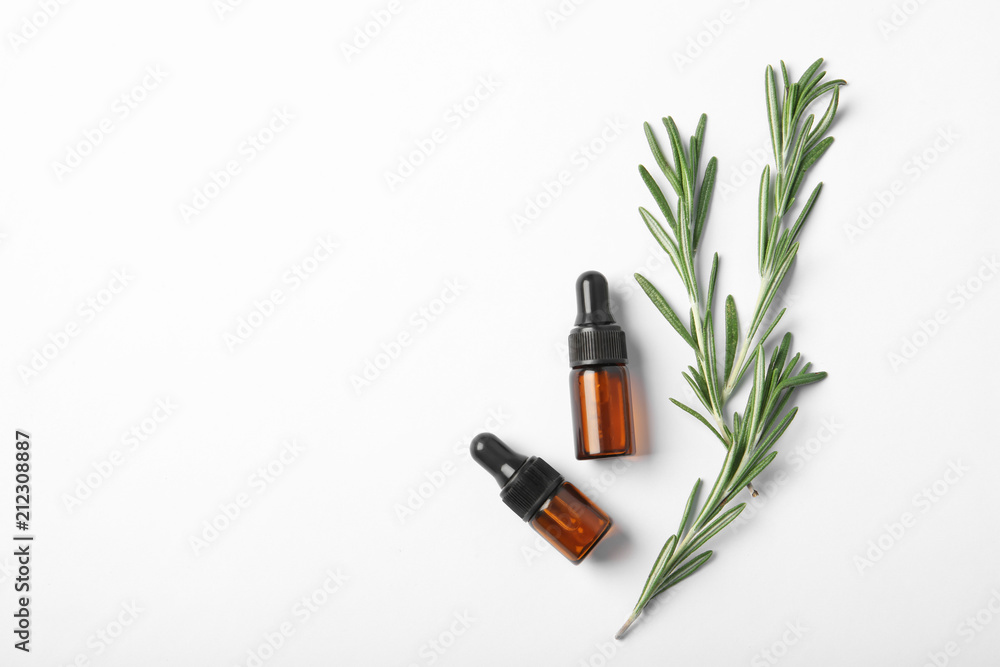 Bottles of rosemary oil and fresh twigs on white background, top view - obrazy, fototapety, plakaty 
