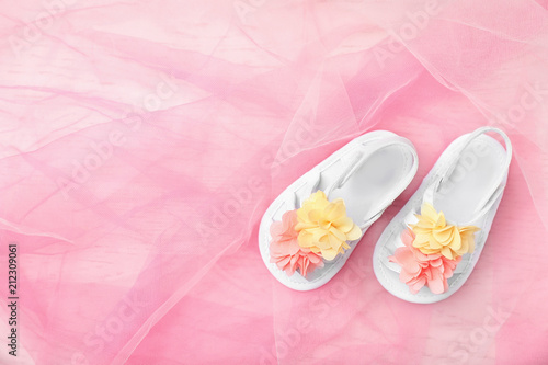 Pair of cute baby sandals on color fabric, top view