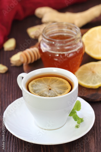 Cup of ginger tea with honey and lemon on wooden table