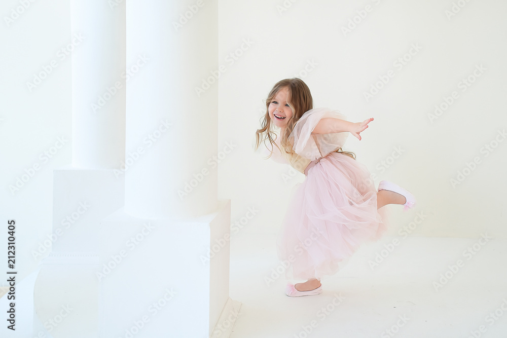 Funny little girl dressed like a princess runs around the column in the room Funny little girl dressed like a princess runs around the column in the room