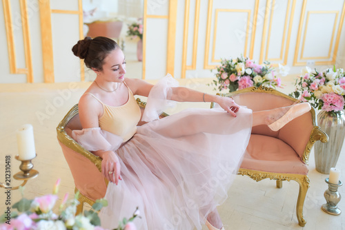 Beautiful ballerina in pink clothes poses in a luxury room photo