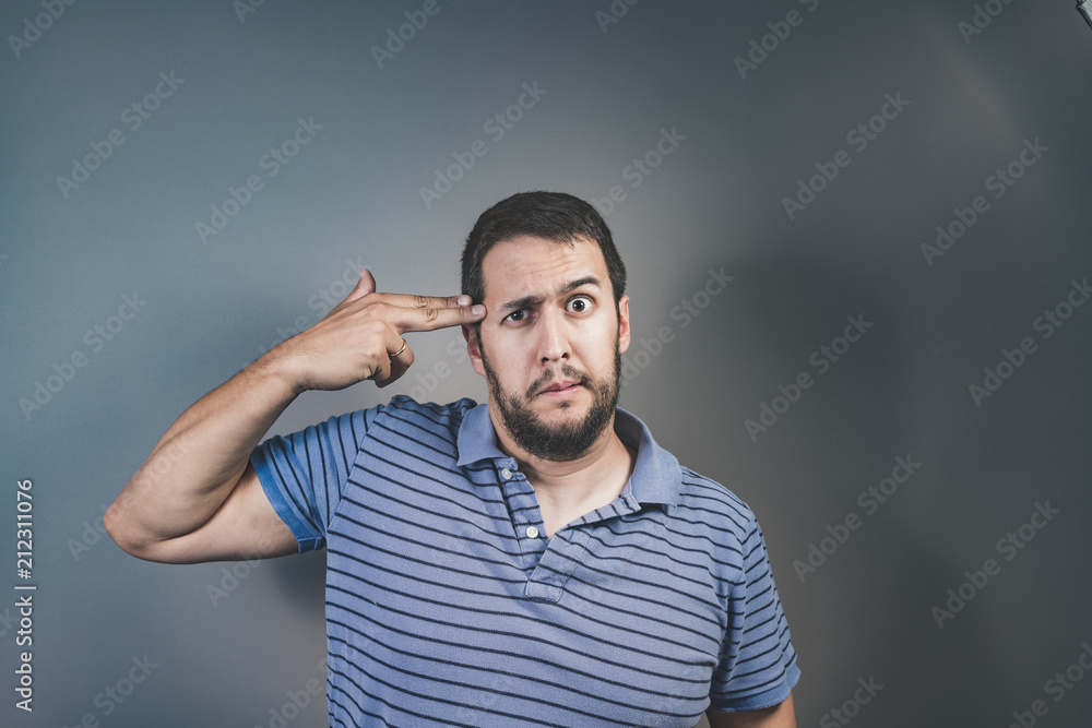 handsome young man pretending to shoot himself with his hand as a gun handsome young man pretending to shoot himself with his hand as a gun