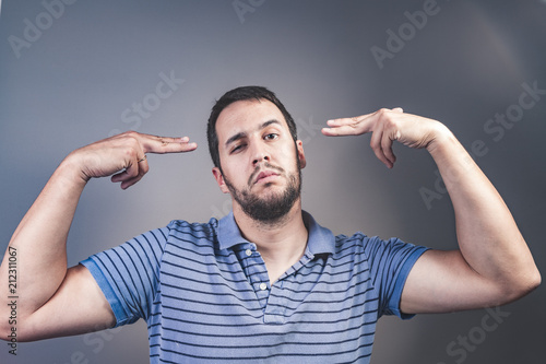 handsome young man pretending to shoot himself with his hand as a gun