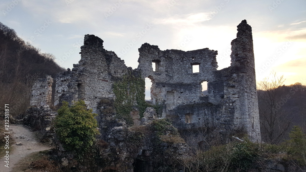 Old castle stone tower ruins of old city Samobor, Croatia surrounded with dense forest and plant overgrowth at sunset