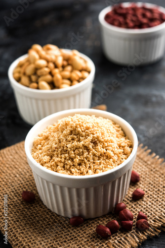 Crushed peanuts or mungfali powder with whole and roasted groundnut. Served in a bowl over moody background. Selective focus photo