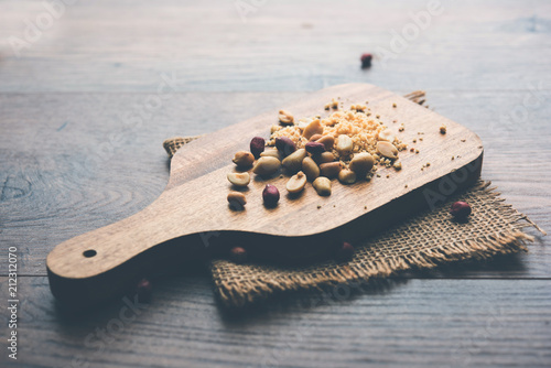 Crushed peanuts or mungfali powder with whole and roasted groundnut. Served in a bowl over moody background. Selective focus photo