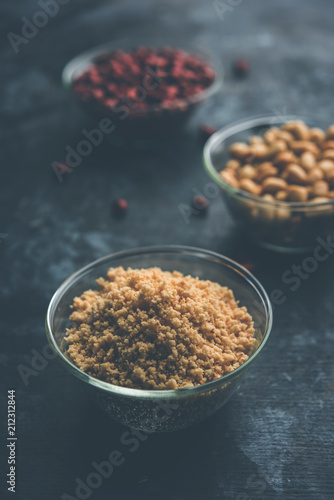 Crushed peanuts or mungfali powder with whole and roasted groundnut. Served in a bowl over moody background. Selective focus photo