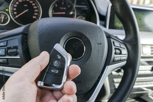 Man's hand holding a wireless  car key in black leather interior. Modern Car interior details. Car detailing. Car inside. Car detailing © Aleksei