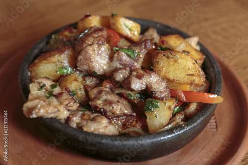 Stew meat in a frying pan with potatoes, vegetables, herbs.