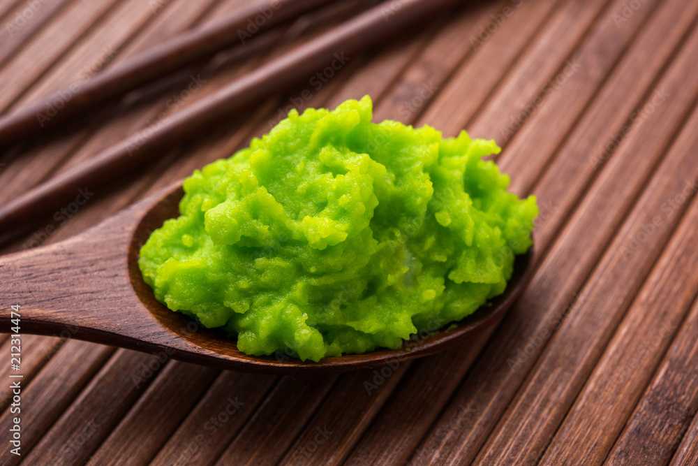Green wasabi sauce or paste in bowl, with chopsticks or spoon over plain colourful background. selective focus Green wasabi sauce or paste in bowl, with chopsticks or spoon over plain colourful background. selective focus