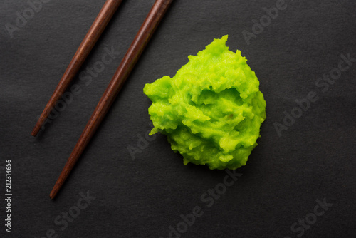 Photo Green wasabi sauce or paste in bowl, with chopsticks or spoon over plain colourful background