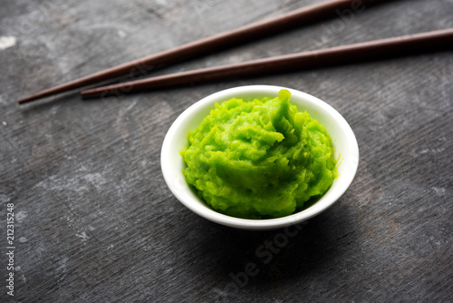 Obraz na plátně Green wasabi sauce or paste in bowl, with chopsticks or spoon over plain colourful background