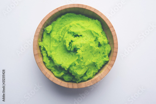 Wallpaper Mural Green wasabi sauce or paste in bowl, with chopsticks or spoon over plain colourful background