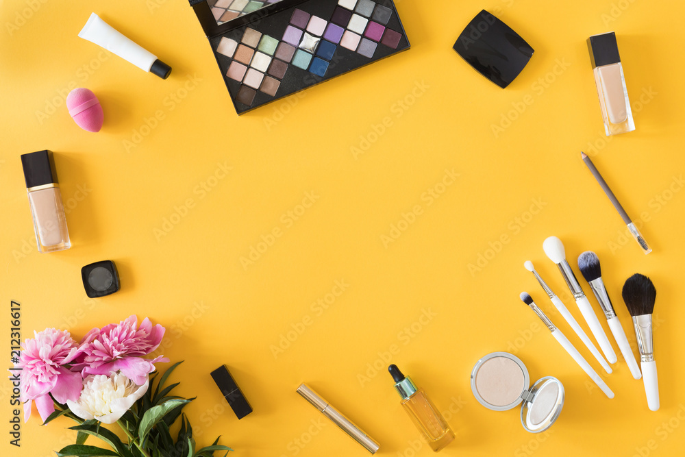 Makeup products with flowers and mobile phone on yellow background. Beauty background, flat lay, top view Makeup products with flowers and mobile phone on yellow background. Beauty background, flat lay, top view