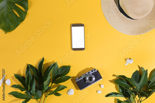 Flat lay on yellow background with mobile phone with white screen, palm leaf,...