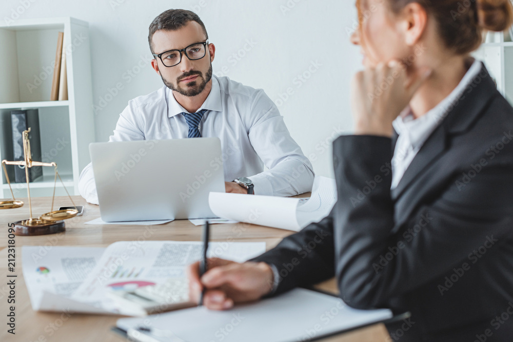 financiers looking at each other at table in office financiers looking at each other at table in office