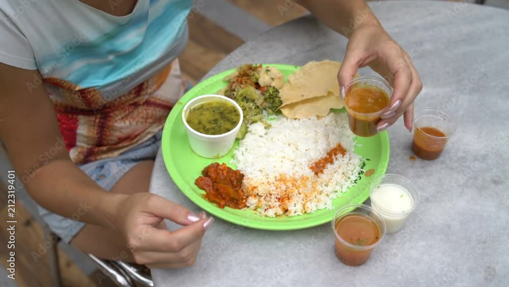 Street Indian food Thali. Woman watering rice sauces Street Indian food Thali. Woman watering rice sauces