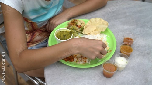 Street Indian food Thali. Woman pours rice with sauce and eats with her hands