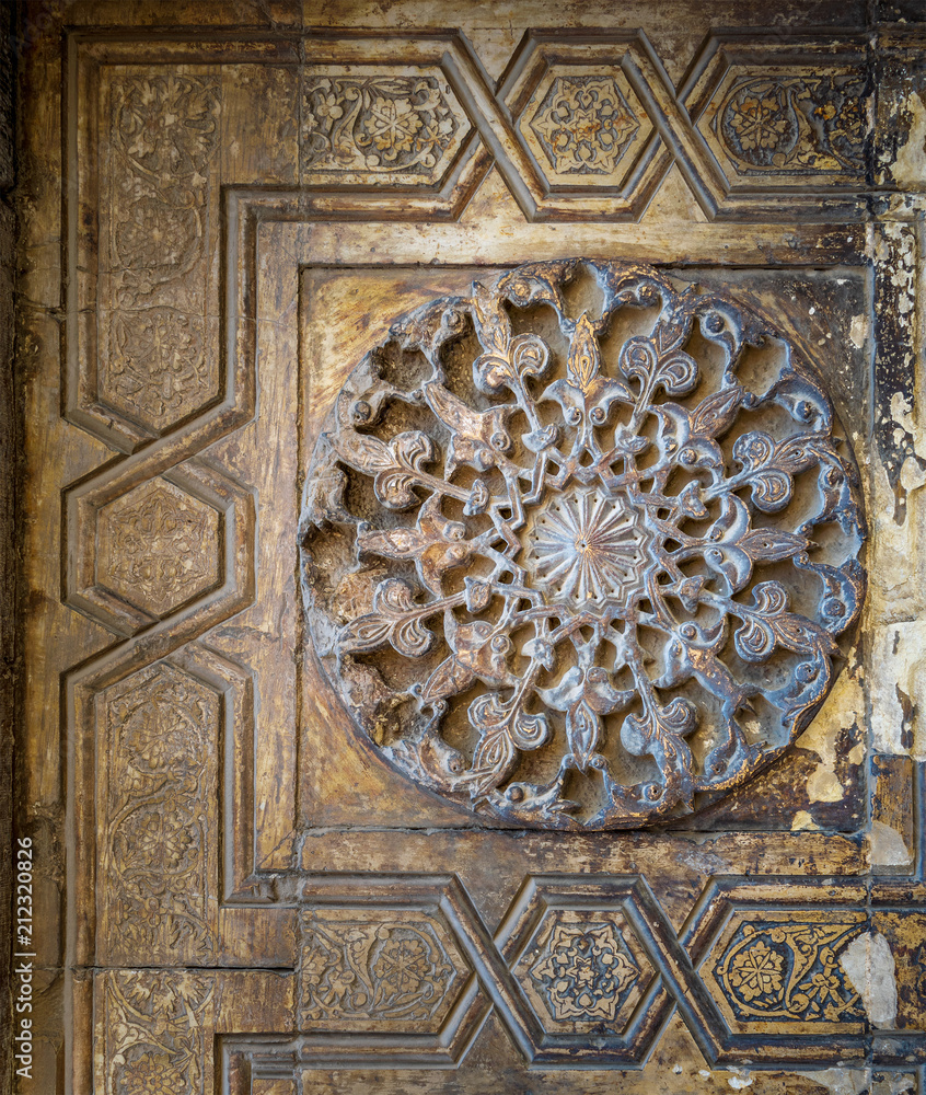 Round floral patterns framed by geometrical patterns carved into the exterior ancient stone wall of Sultan Hasan Mosque, Old Cairo, Egypt Round floral patterns framed by geometrical patterns carved into the exterior ancient stone wall of Sultan Hasan Mosque, Old Cairo, Egypt