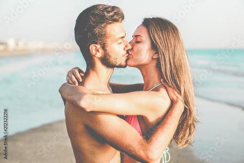 Young lovers kissing in summer vacation next to the ocean