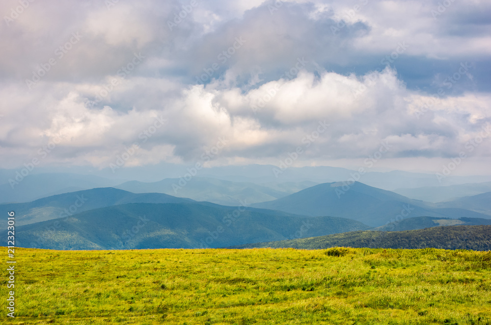 grassy alpine meadow in cloudy weather. beautiful landscape of Carpathian mountain in the distance. gorgeous cloud formation above. lovely flat minimalist scenery in summer