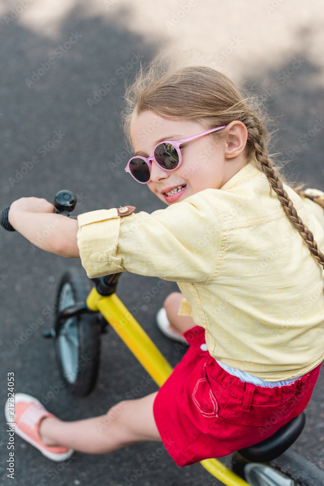 Fototapeta premium adorable smiling child in sunglasses riding bicycle
